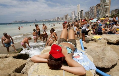 Una turista toma el sol sobre las rocas en una playa en Benidorm. / EFE