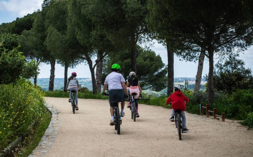 Una familia monta en bicicleta por la Dehesa de la Villa.