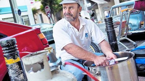 Un integrante del movimiento &ldquo;comida para todos&rdquo; prepara una olla popular en el centro de Atenas.