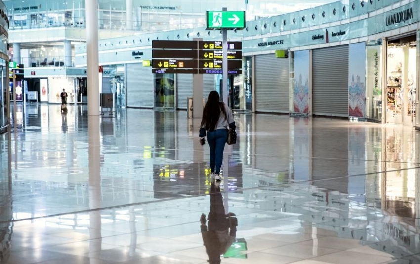 Una pasajera camina sola en la zona comercial de El Prat